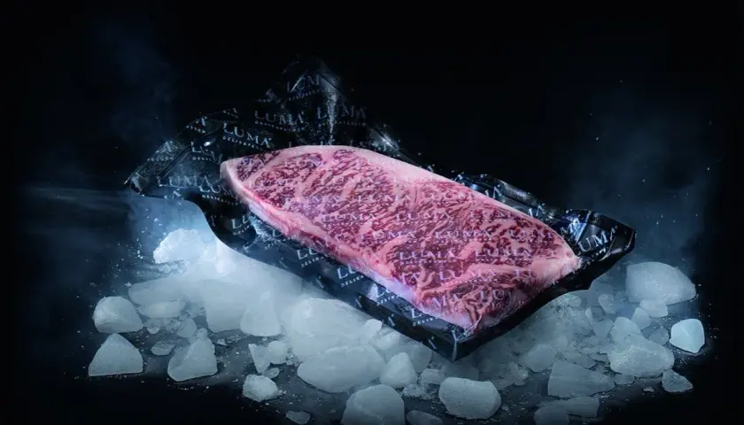 Un beau morceau de viande de bœuf marbré, emballé sous vide, posé sur de la glace pilée. Le processus pour décongeler viande est sur le point de commencer.