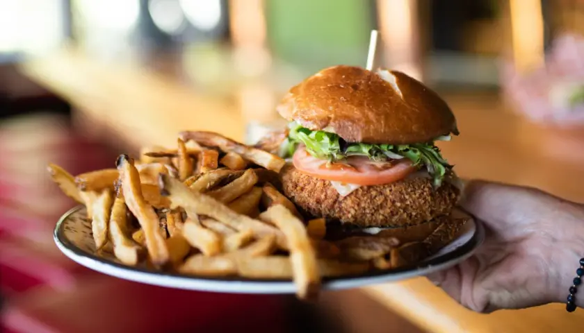 Un délicieux burger montagnard, croustillant et garni, servi avec une généreuse portion de frites dorées.