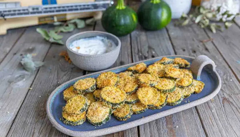 Galette de courgette parmesan au four, croustillante et dorée, servie avec une sauce crémeuse. Un délice simple et savoureux.