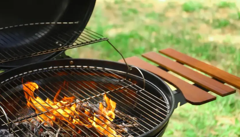 Un barbecue au feu de bois, prêt pour une belle journée ensoleillée. Les flammes dansent sur les braises, promettant de délicieux moments.