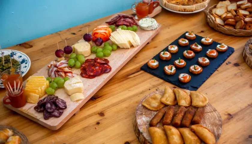Un buffet champêtre gourmand : planches de charcuterie, fromages, raisins, mini-quiches et toasts saumon.