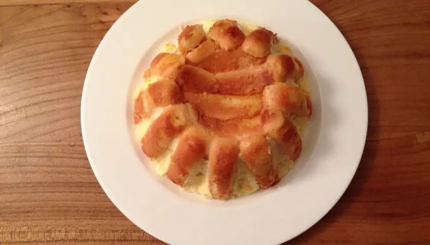 Charlotte à l'orange, un dessert doré et moelleux, servi sur une assiette blanche.