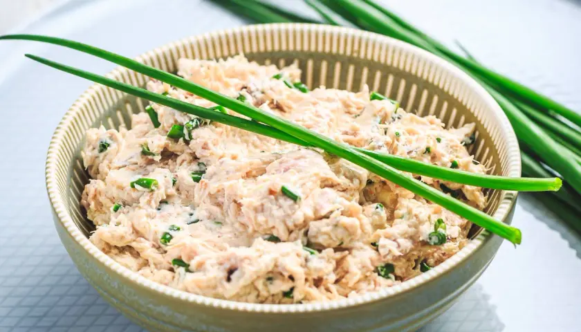 Un bol de rillettes de thon à la crème fraîche, garni de ciboule fraîche. Un délice crémeux et savoureux.