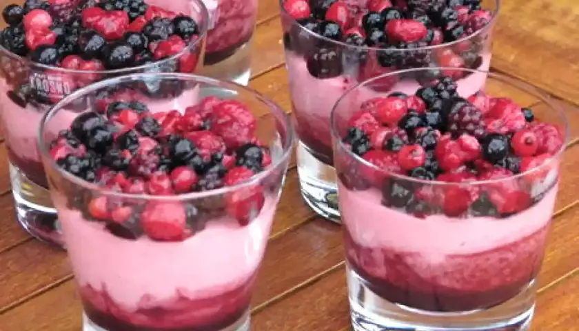 Plusieurs verrines de **dessert léger aux fruits rouges surgelés**, garnies de baies fraîches et d'une mousse rose.