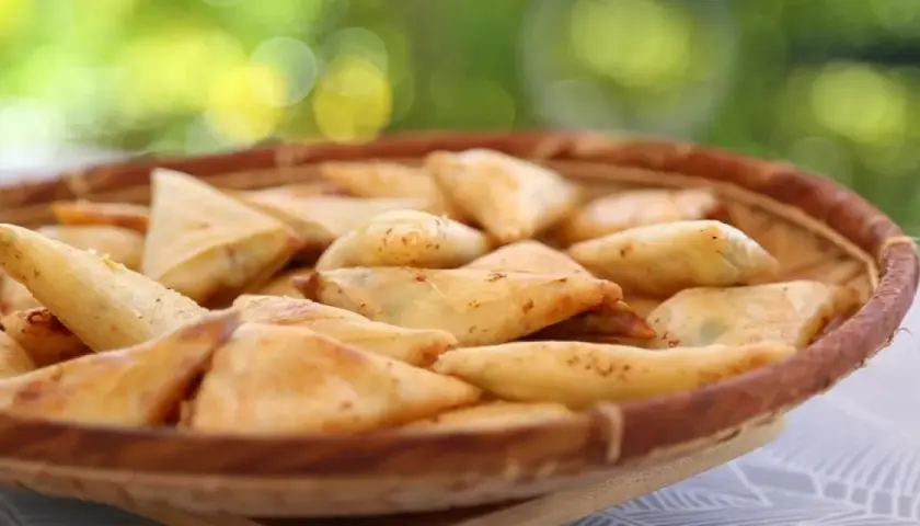 Un panier rempli de samoussas dorés, garniture pomme de terre fromage. Parfait pour un apéritif gourmand en extérieur.