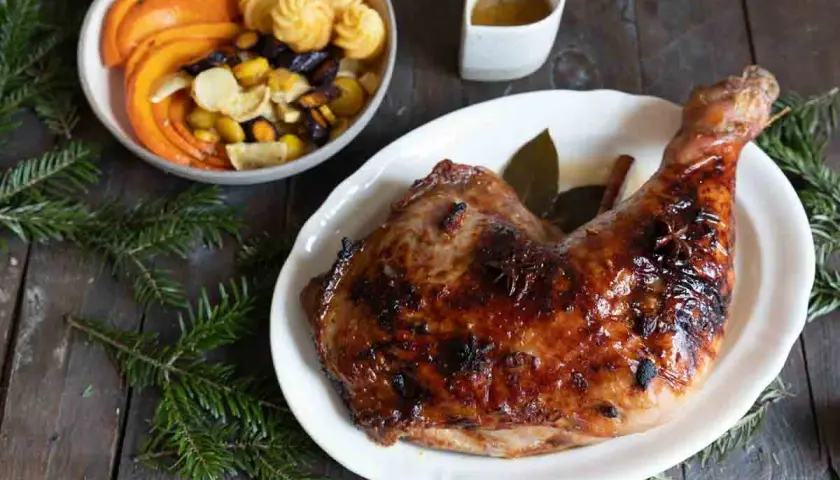 Une cuisse de dinde rôtie, brillante et savoureuse, parfaite pour une recette cuisse de dinde originale. Accompagnée de légumes et de petites bouchées.
