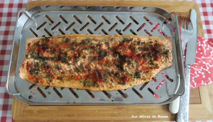 Filet de truite au four, parsemé d'herbes et de baies roses, prêt à être dégusté.