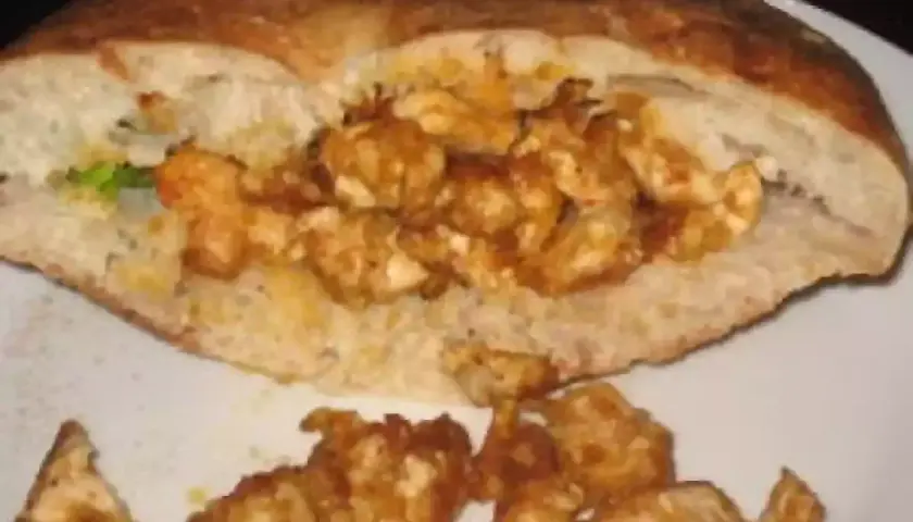 Un pain garni de morceaux de poulet épicés, prêt à déguster. Une recette kebab maison facile pour un repas savoureux.