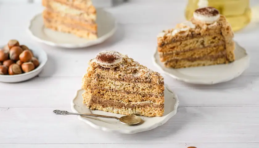 Tranches de gâteau moelleux aux noisettes de ma mamie, garnies de crème au chocolat et saupoudrées de cacao. Un délice !