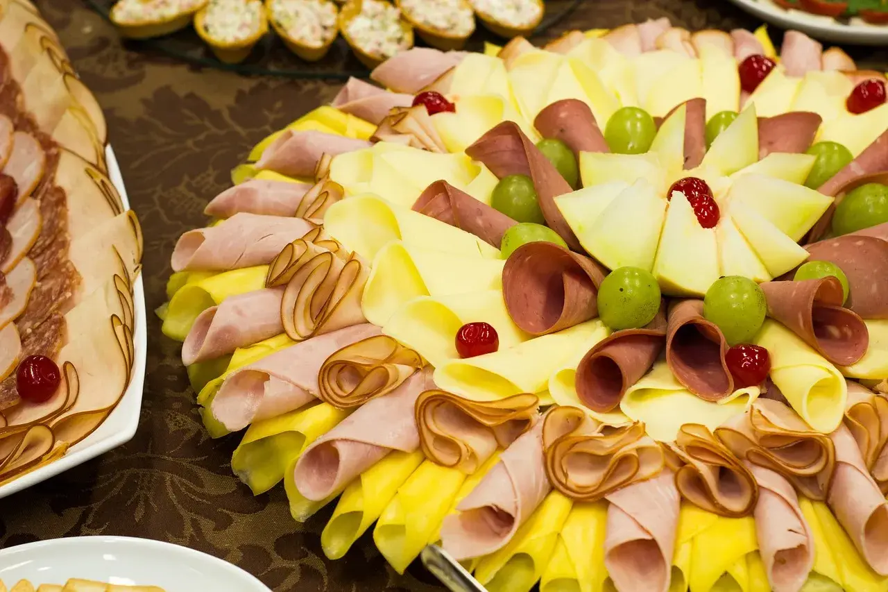 Un buffet froid facile et pas cher : plateau de charcuterie, fromages roulés, raisins verts et cerises confites.