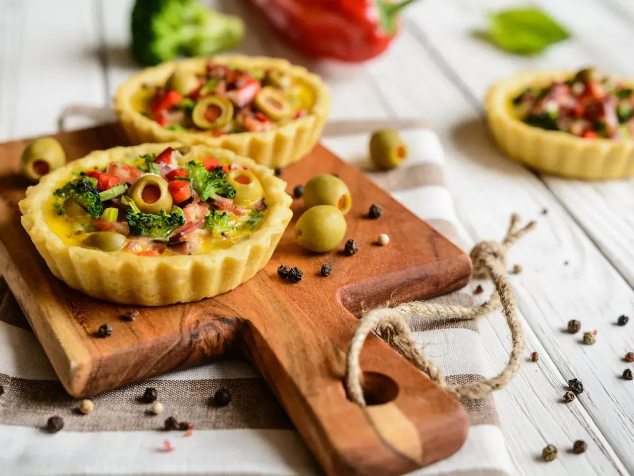 Mini quiches colorées sur fond de bois blanc, une idée pour que faire avec un reste de pâte brisée.