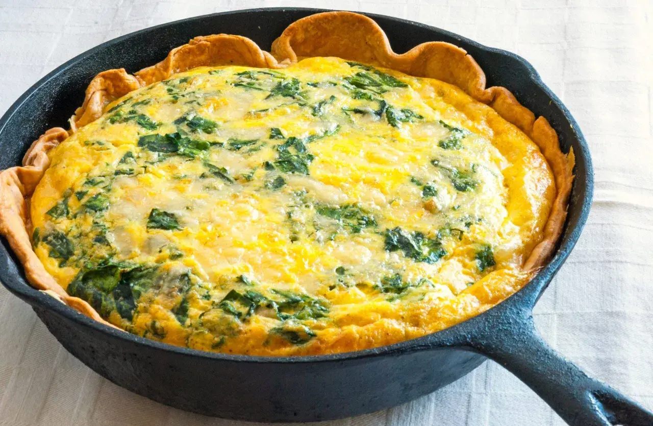 Quiche aux épinards dans une poêle en fonte, parfaite pour une recette jaune d'oeuf.
