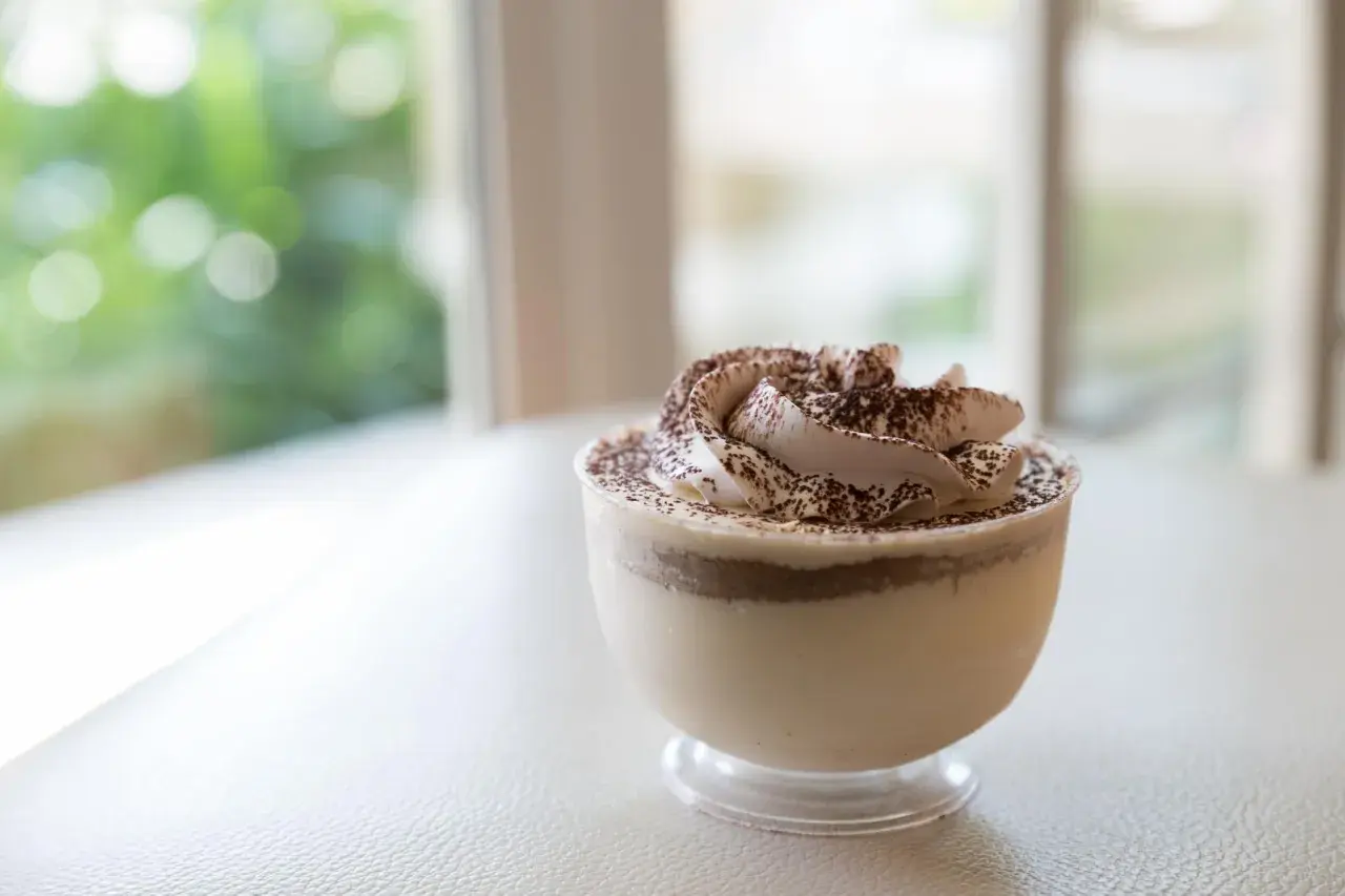 Délicieuse mousse au café sans cuisson, garnie de cacao, dans un verre transparent. Parfait pour une pause gourmande.