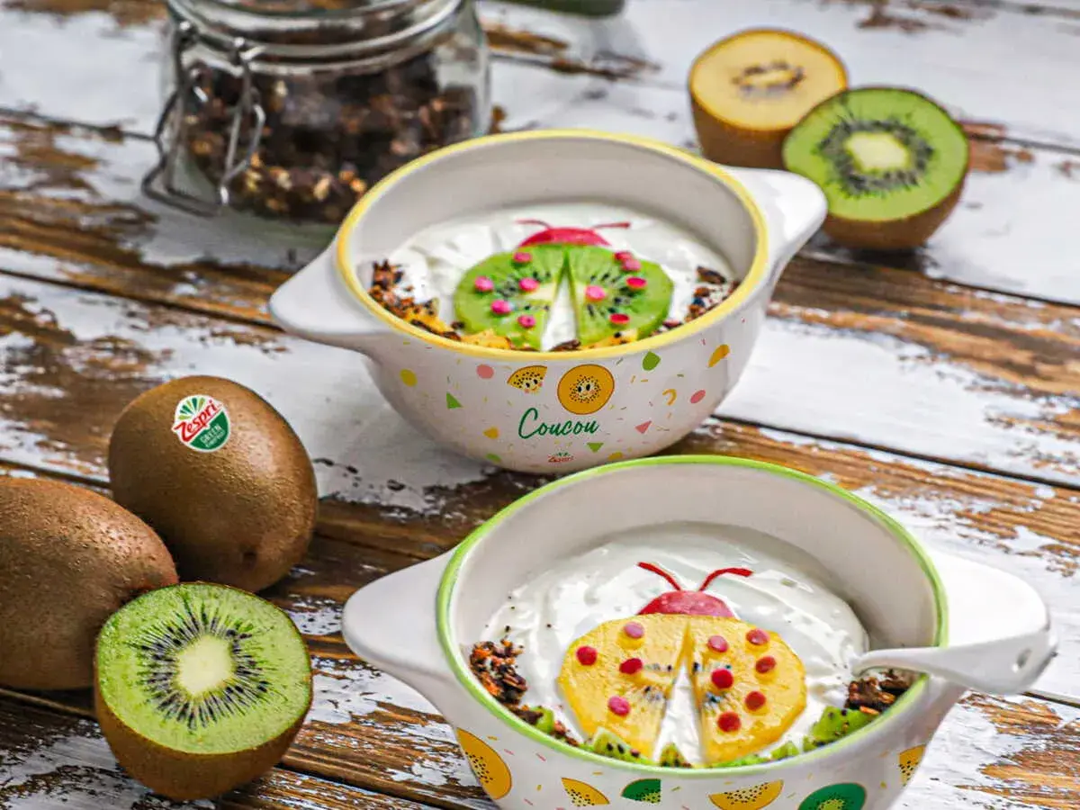 Recette kiwi trop mûr : yaourt et granola décorés d'une coccinelle en kiwi et fruits rouges. Parfait pour un petit-déjeuner ludique.