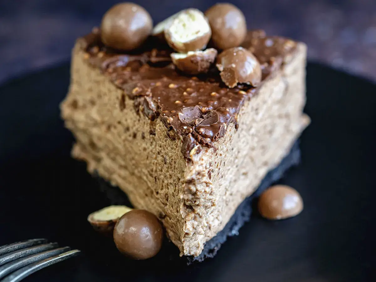 Une part de gâteau au chocolat aérien, garnie de boules Malteser croquantes et d'un glaçage au chocolat.