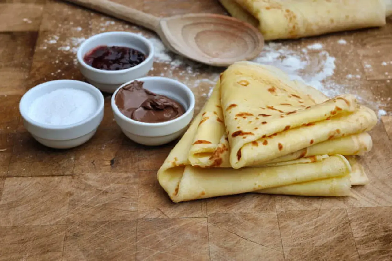 Crêpes sans lactose dorées, accompagnées de confiture, pâte à tartiner et sucre. Un délice pour tous !