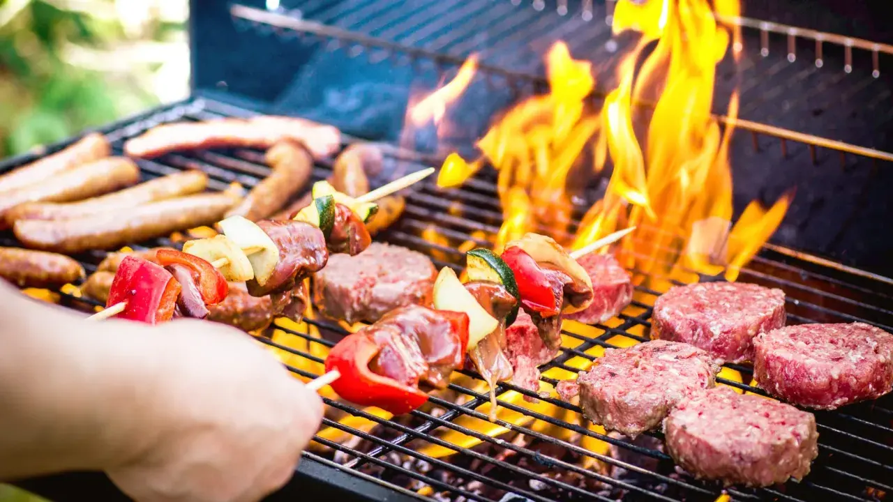 Brochettes et steaks sur un barbecue en feu. La conservation de la viande cuite au barbecue est essentielle pour profiter des restes.