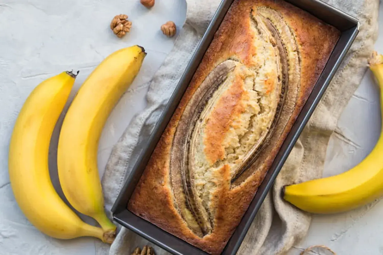 Gâteau moelleux à la banane trop mûre, cuit à la poêle, avec des bananes fraîches et des noix autour.