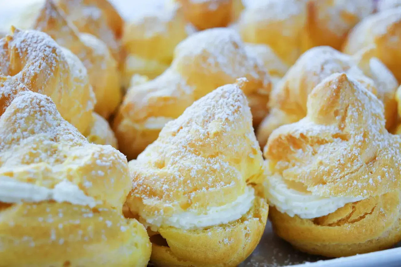 Choux garnis de crème, saupoudrés de sucre glace. Pour qu'ils restent gonflés, il faut bien cuire la pâte à choux et ne pas ouvrir le four trop tôt.
