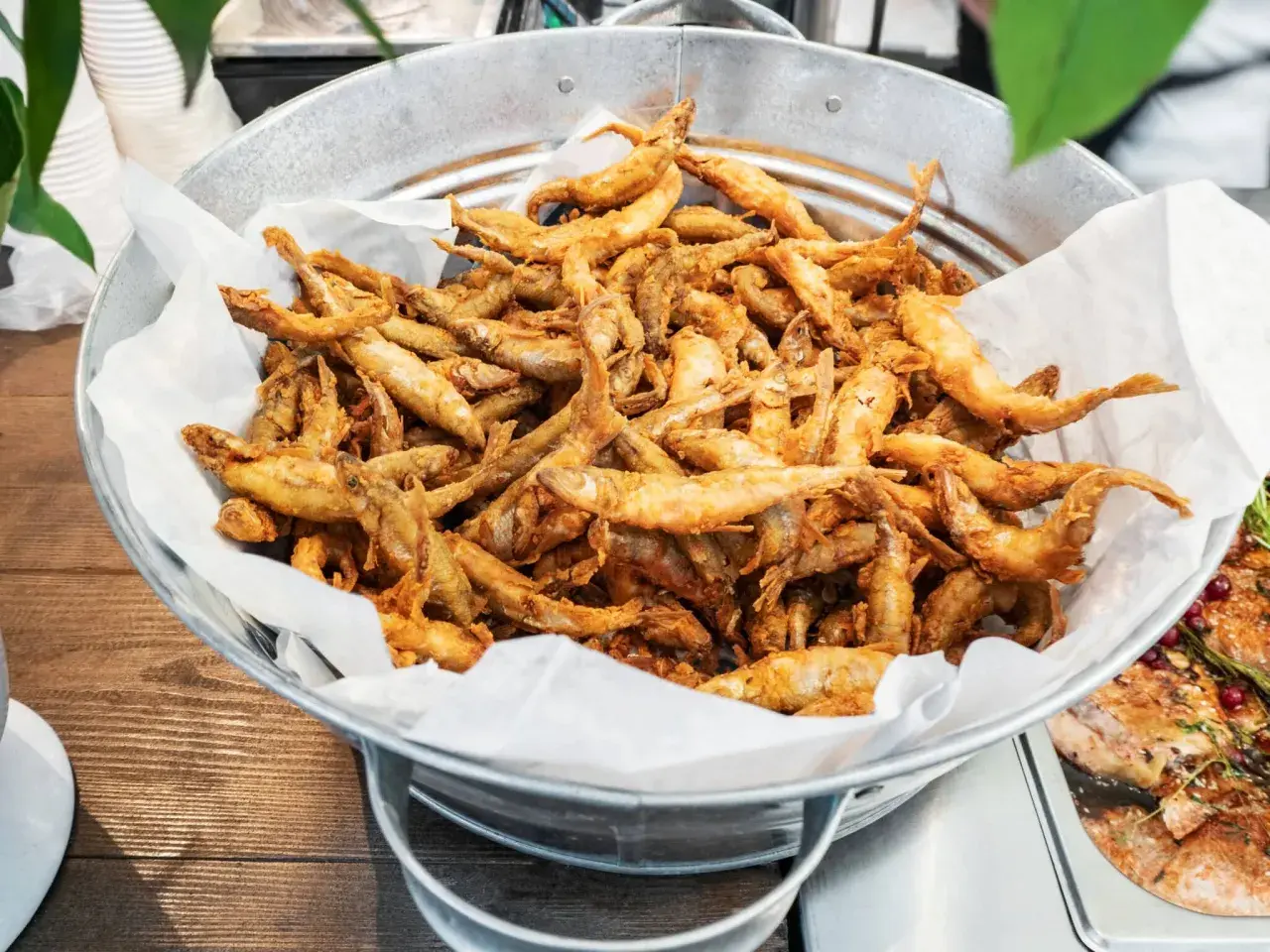 Un seau rempli d'éperlans frits dorés, prêts à être dégustés. Ces petits poissons croustillants sont un délice.