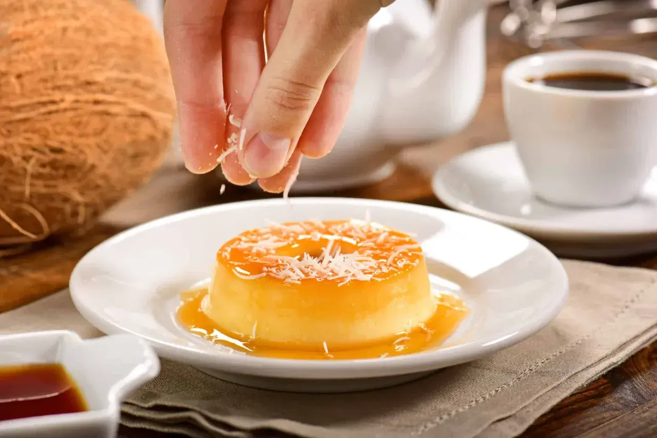 Un flan au lait de coco sans four, garni de noix de coco râpée, prêt à être dégusté avec un café.