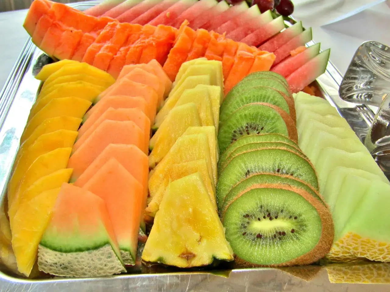 Présentation de fruits pour mariage : plateau coloré de pastèque, melon, papaye, ananas et kiwi coupés en éventail.