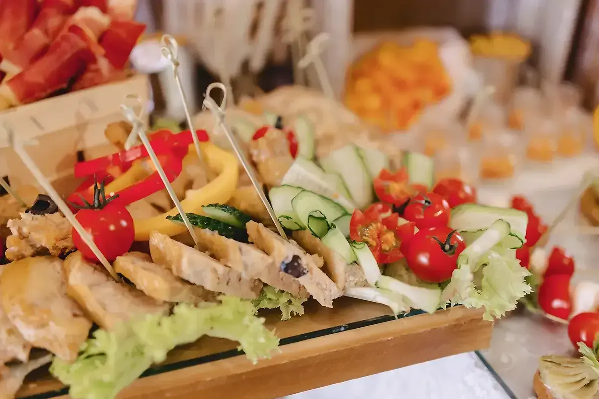 Un buffet froid festif pour un buffet départ retraite : brochettes de tomates cerises, concombres, poivrons et tranches de pain garnies.