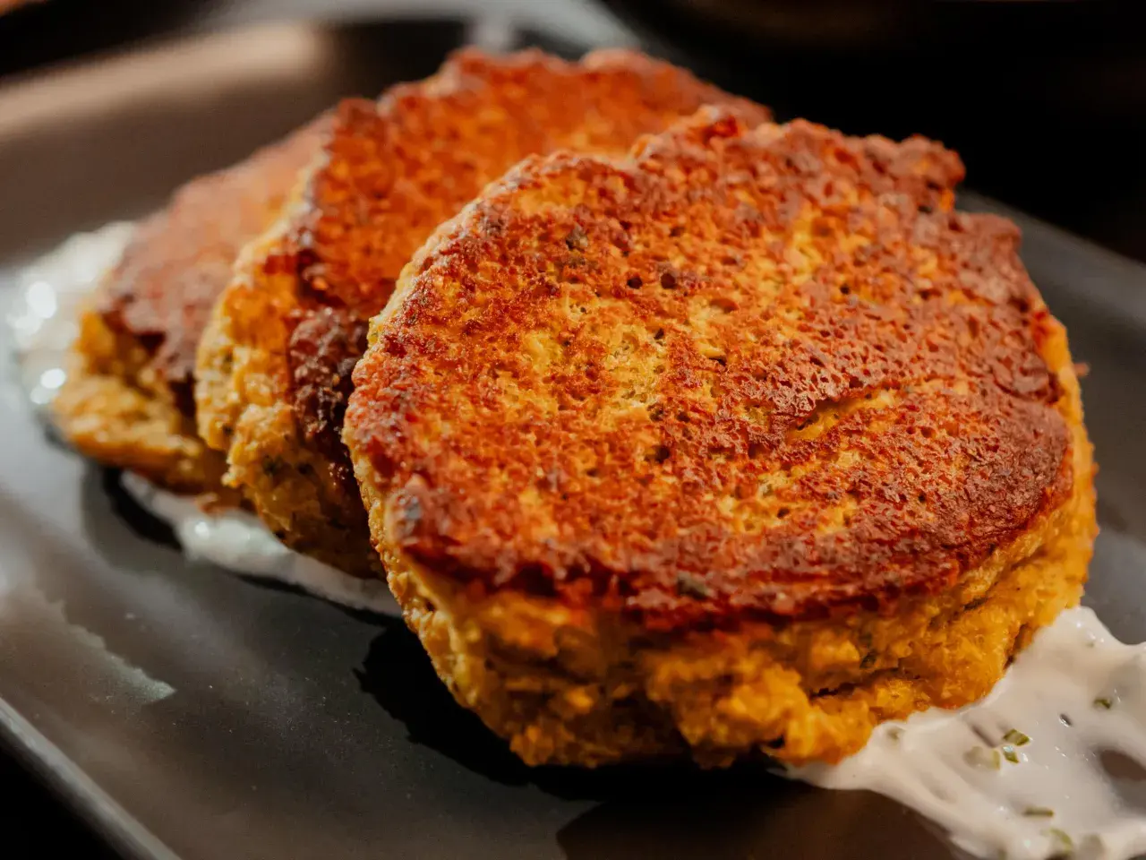Trois galettes dorées de tortilla pois chiche, servies sur une sauce blanche crémeuse.