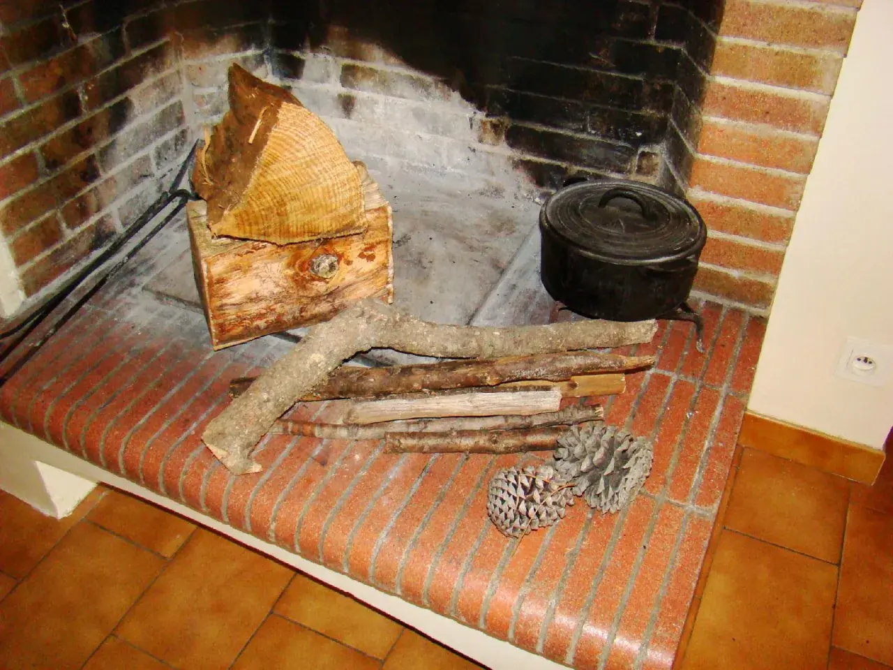 Prêt à allumer le feu avec des pommes de pin, du petit bois et des bûches. Une marmite en fonte est posée près du foyer.