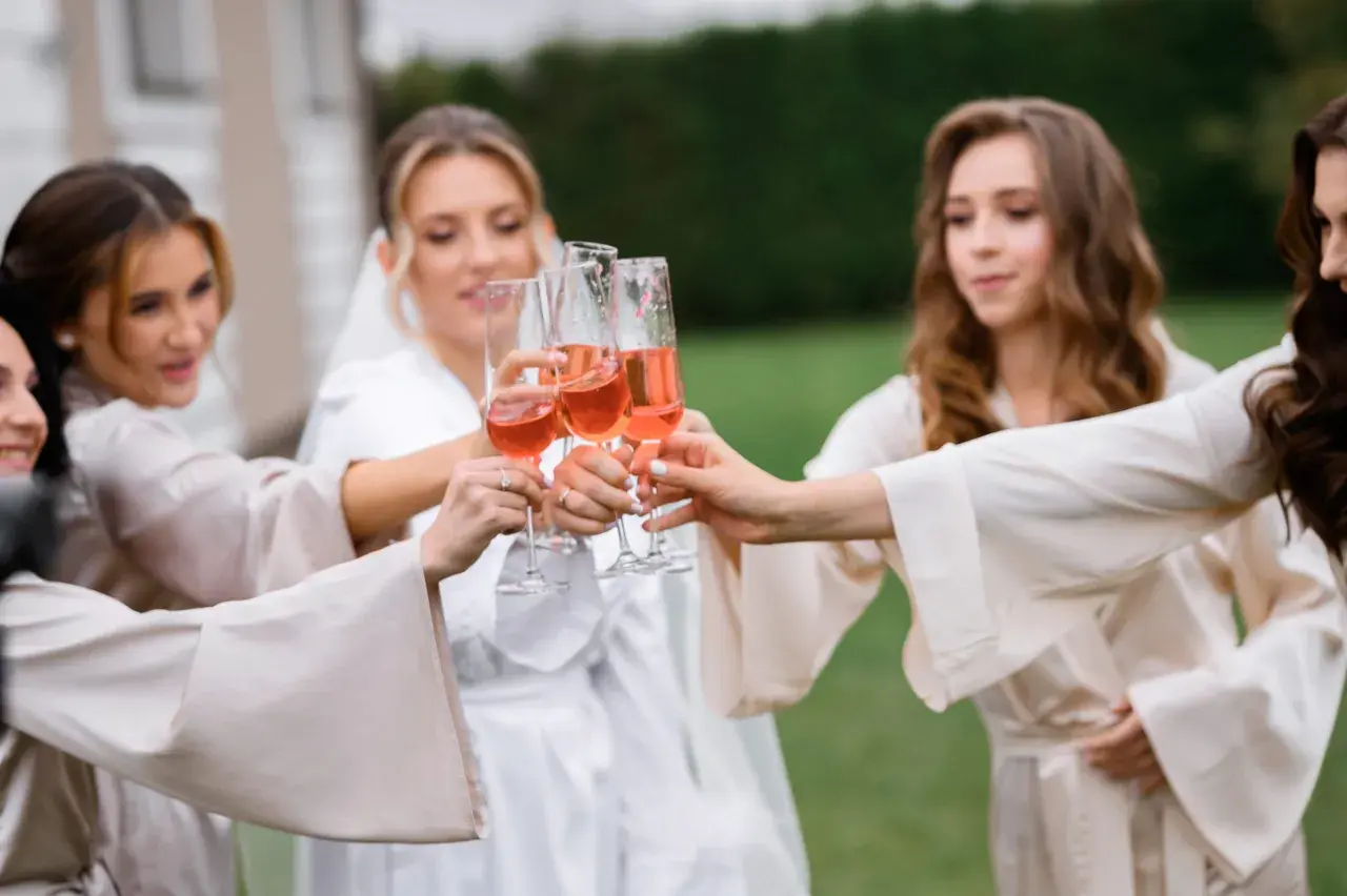Cinq femmes portent des robes de chambre en soie et portent des verres de champagne rosé pour un vin d'honneur à 16h.