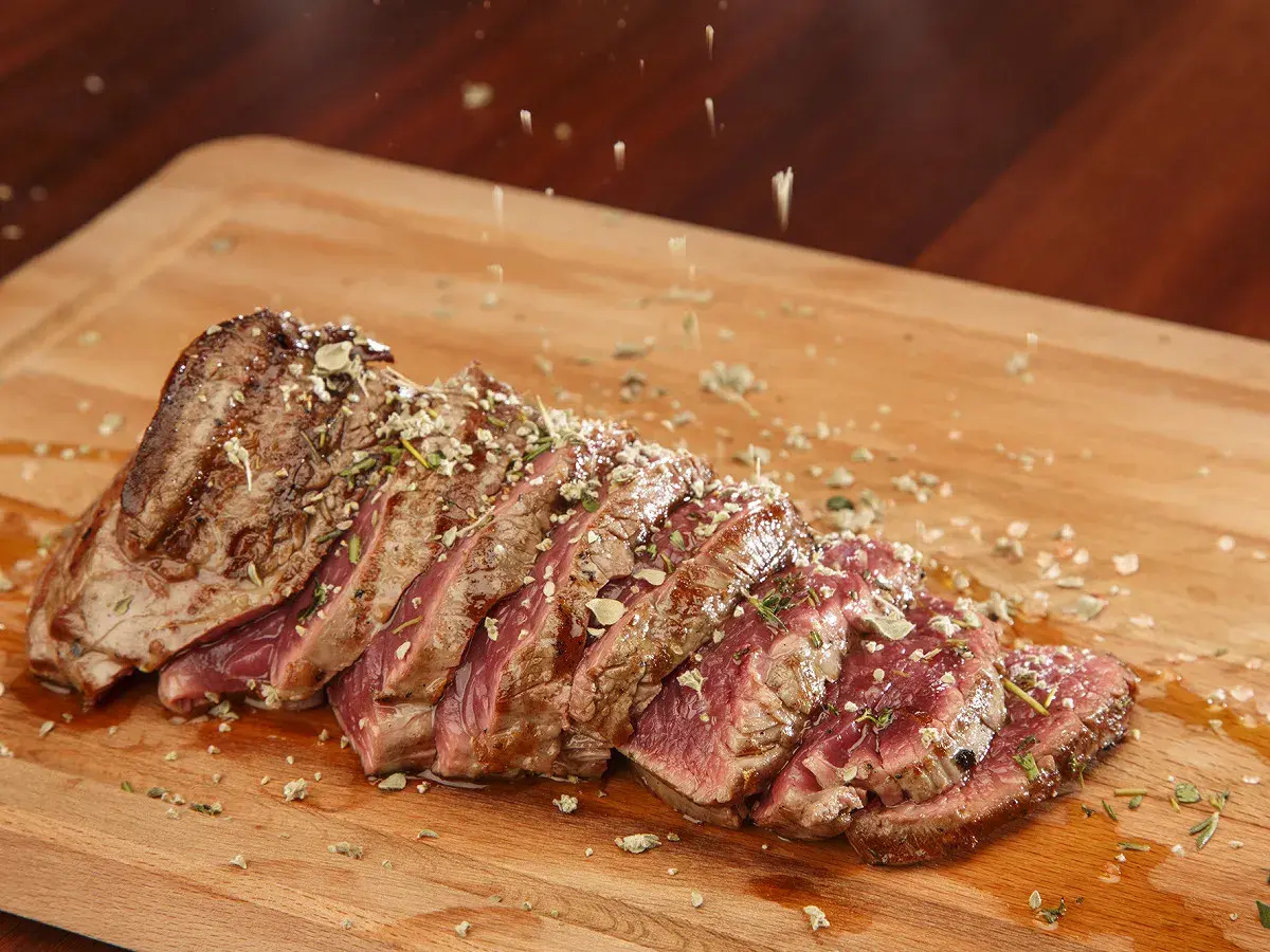 Un succulent côte de bœuf, tranché et parsemé d'herbes, prêt à être dégusté. Une croûte de sel subtile rehausse sa saveur.