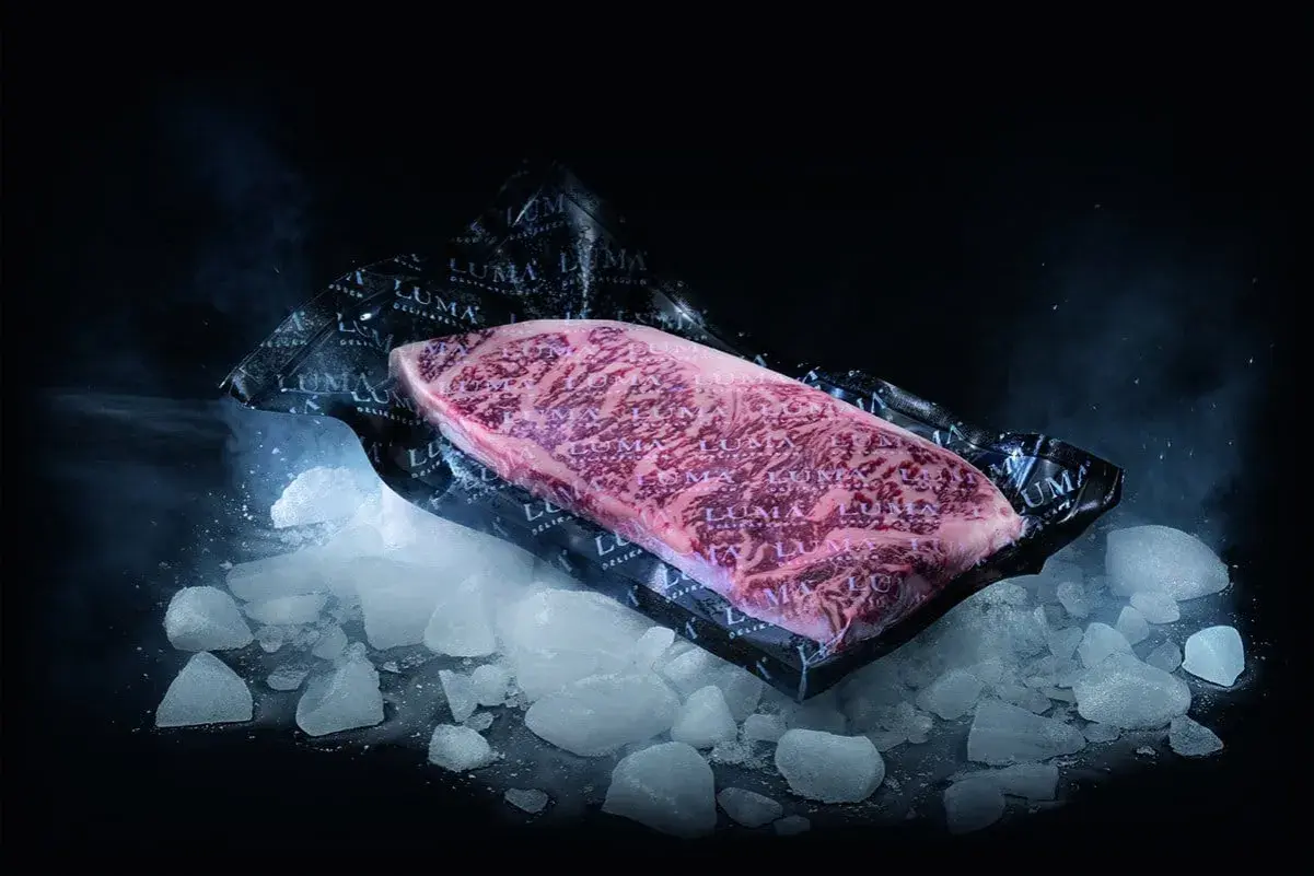 Un beau morceau de viande de bœuf marbré, emballé sous vide, posé sur de la glace pilée. Le processus pour décongeler viande est sur le point de commencer.
