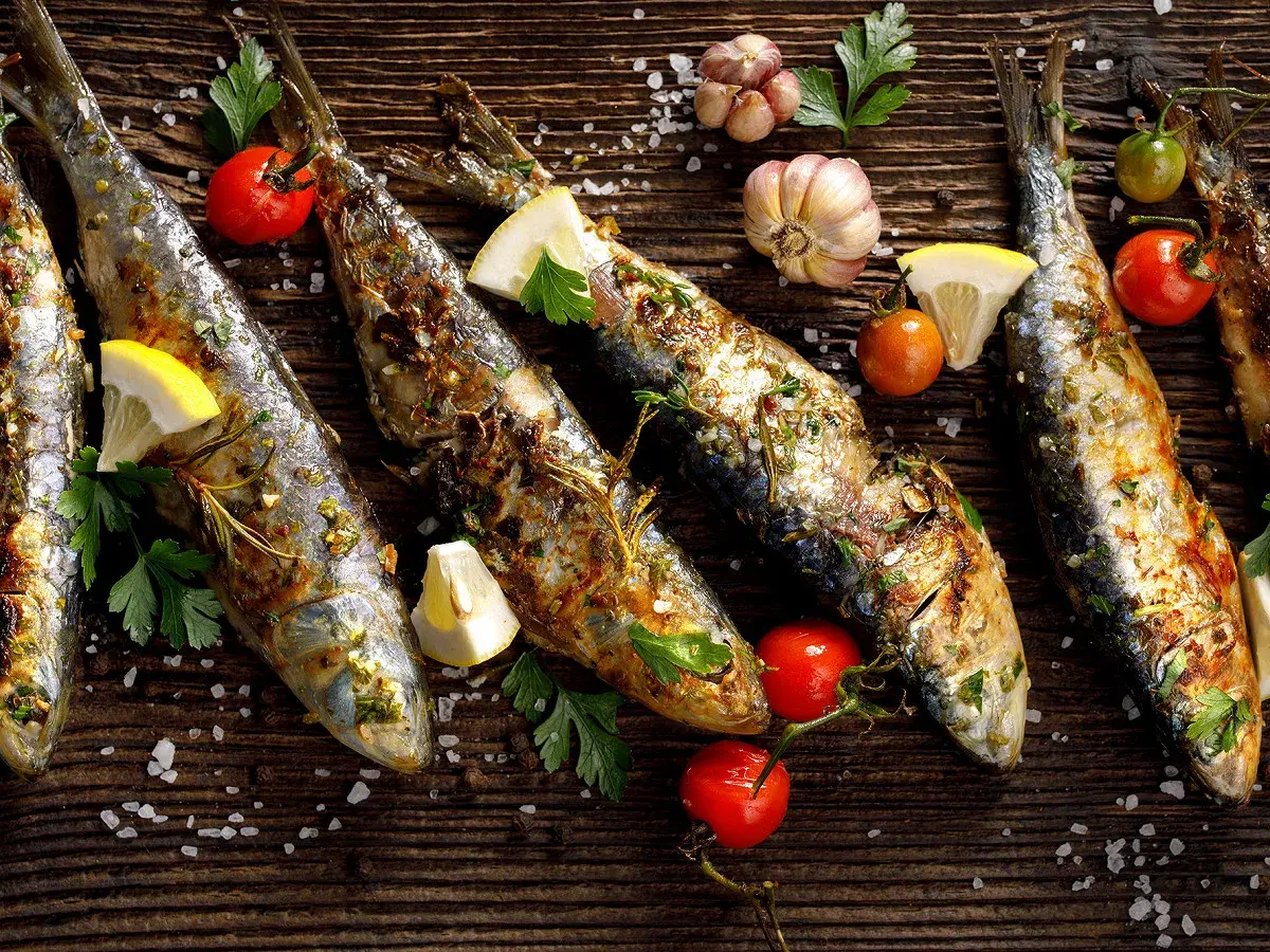 Sardines grillées, citron, tomates cerises et ail sur fond de bois. Faut-il vider les sardines avant de les cuire ?