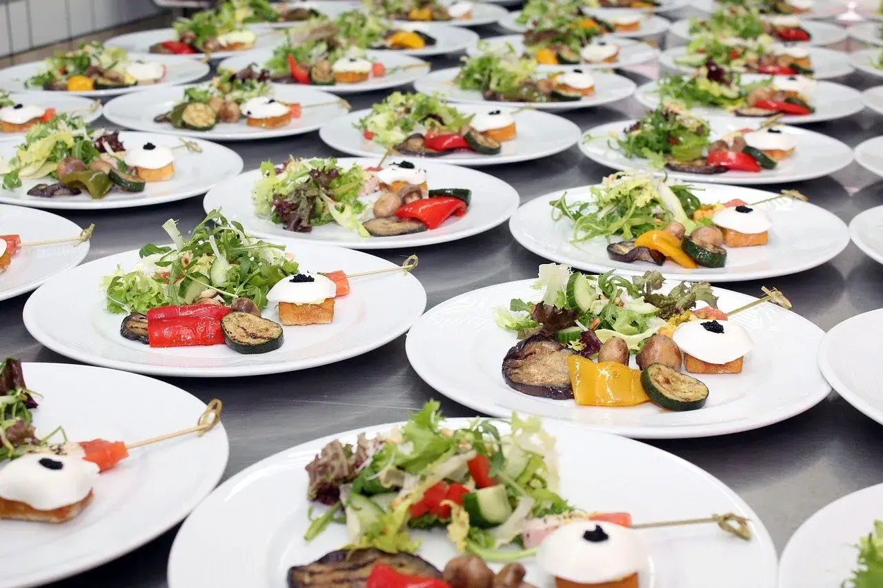 Organisation buffet : assiettes individuelles de salade fraîche, légumes grillés et amuse-bouches joliment dressés, prêts à être servis.