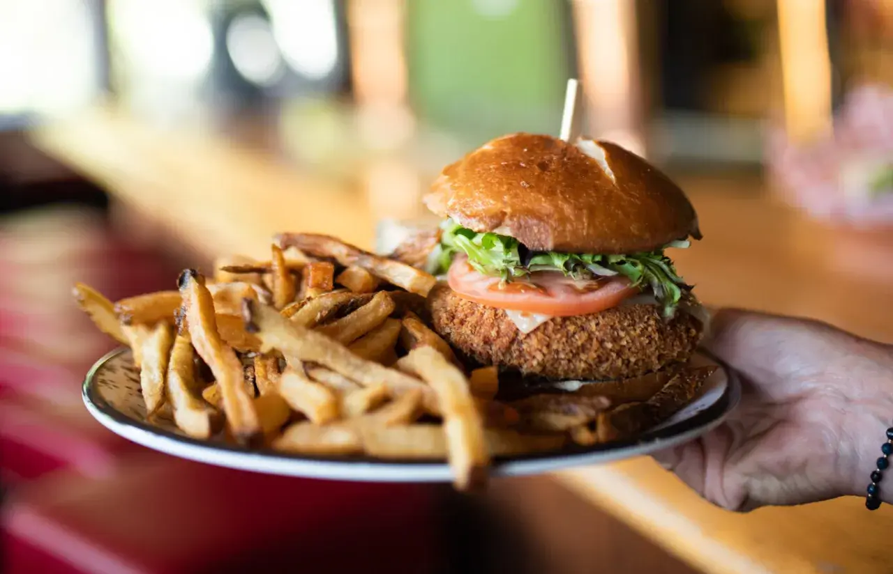Un délicieux burger montagnard, croustillant et garni, servi avec une généreuse portion de frites dorées.