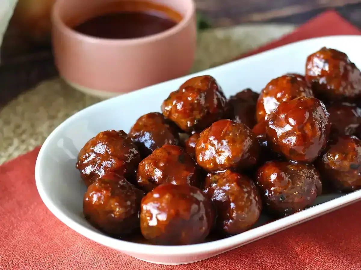 Un plat de boulettes de viande barbecue, brillantes et appétissantes, baignant dans une sauce sucrée. Parfaites pour un apéritif ou un repas convivial.
