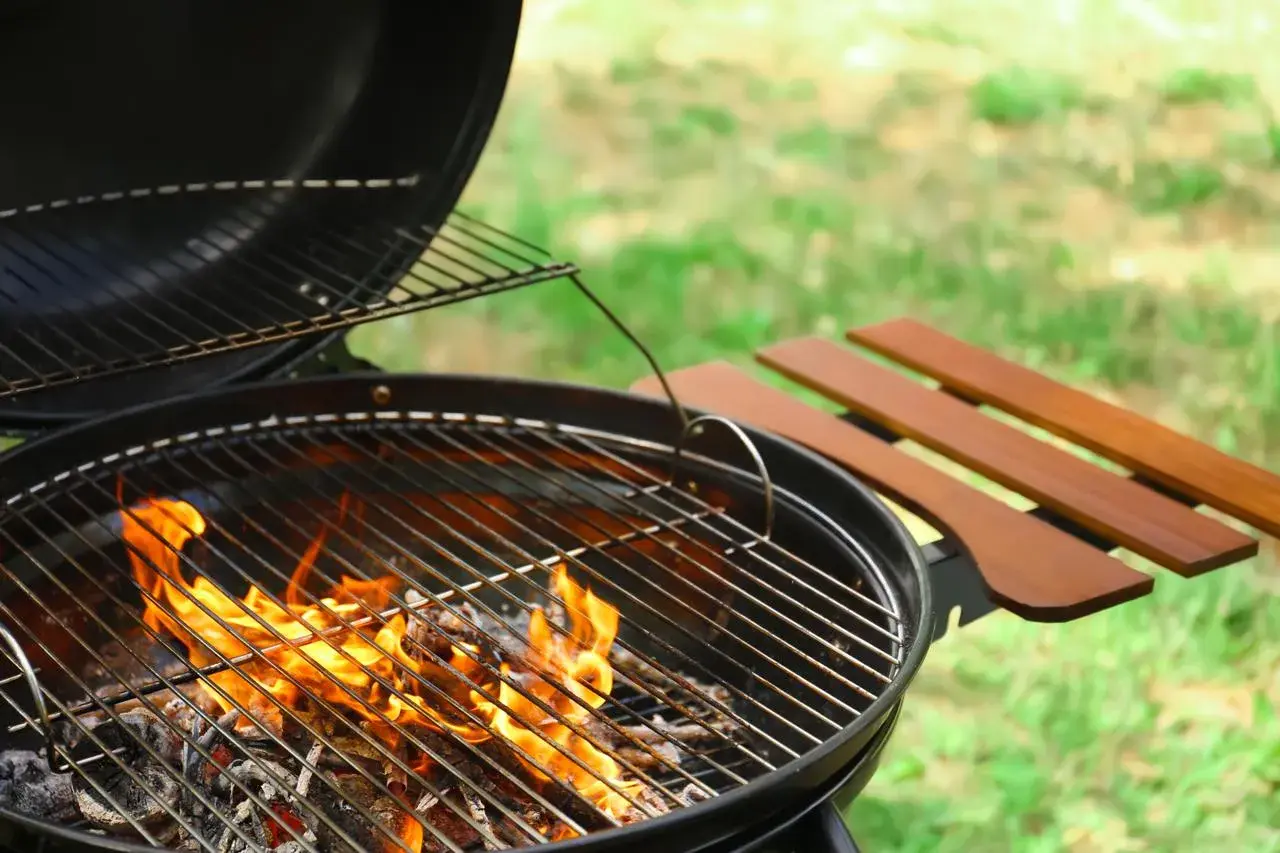 Un barbecue au feu de bois, prêt pour une belle journée ensoleillée. Les flammes dansent sur les braises, promettant de délicieux moments.