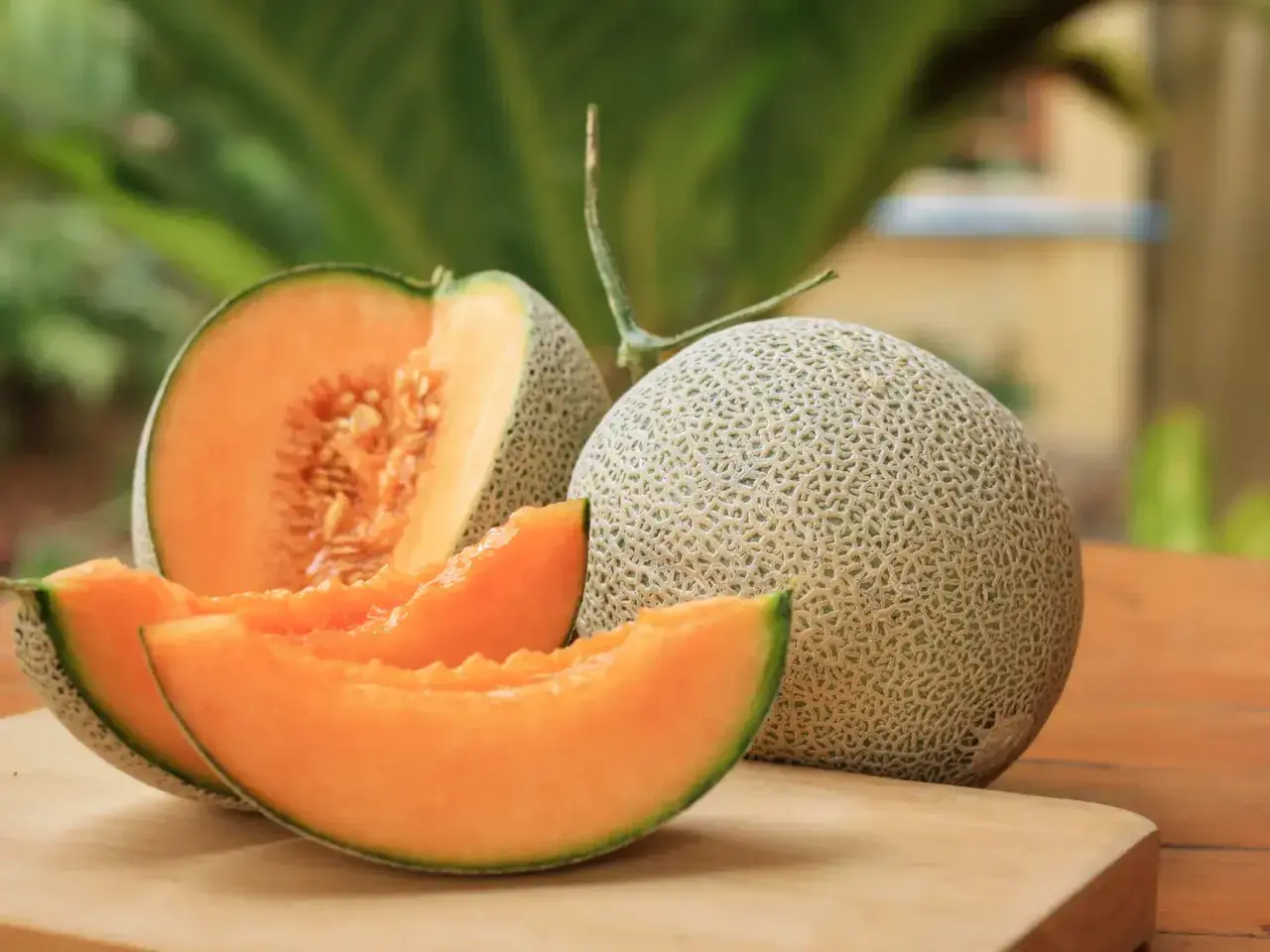 Un melon coupé en quartiers et un entier sur une planche à découper. Idéal pour savoir que faire avec un melon pas bon : le transformer en sorbet !