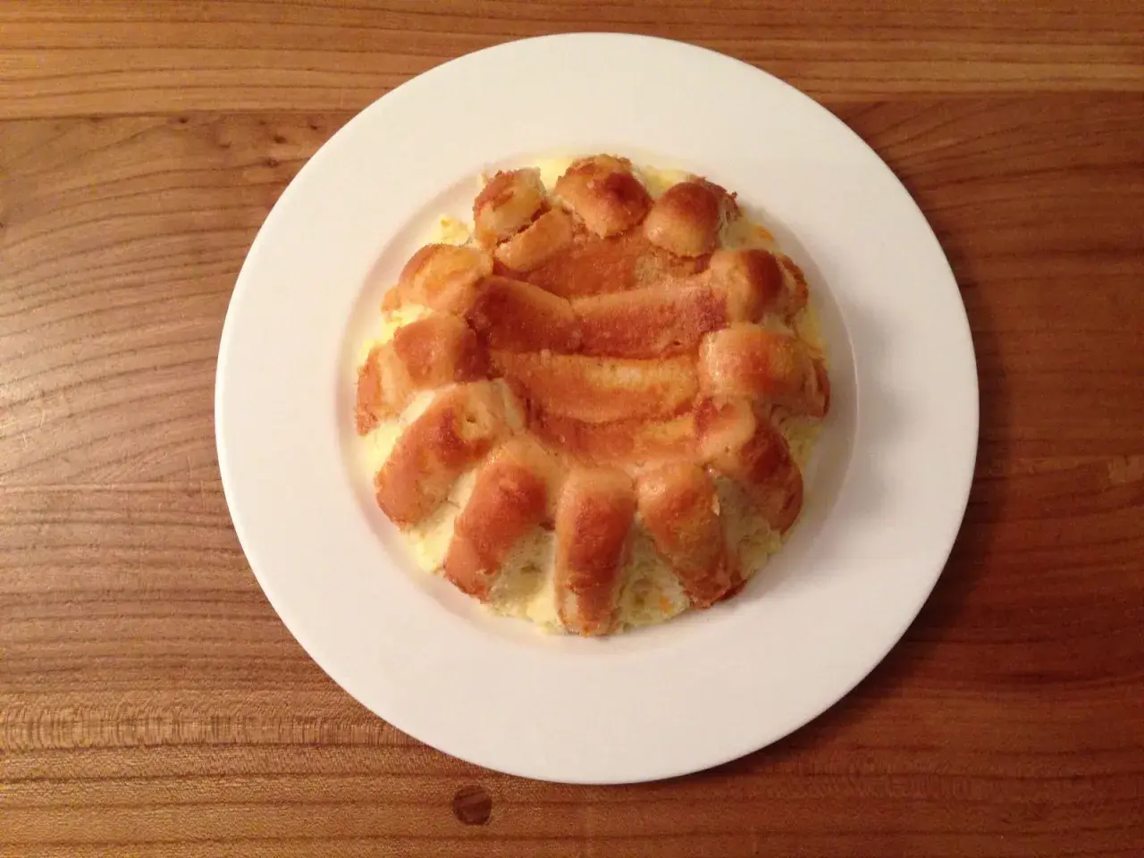 Charlotte à l'orange, un dessert doré et moelleux, servi sur une assiette blanche.
