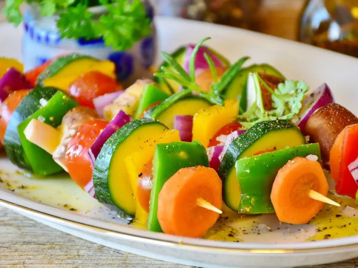 Brochettes de légumes colorées, une excellente idée accompagnement barbecue. Courgettes, poivrons, carottes, tomates et oignons rouges assaisonnés.