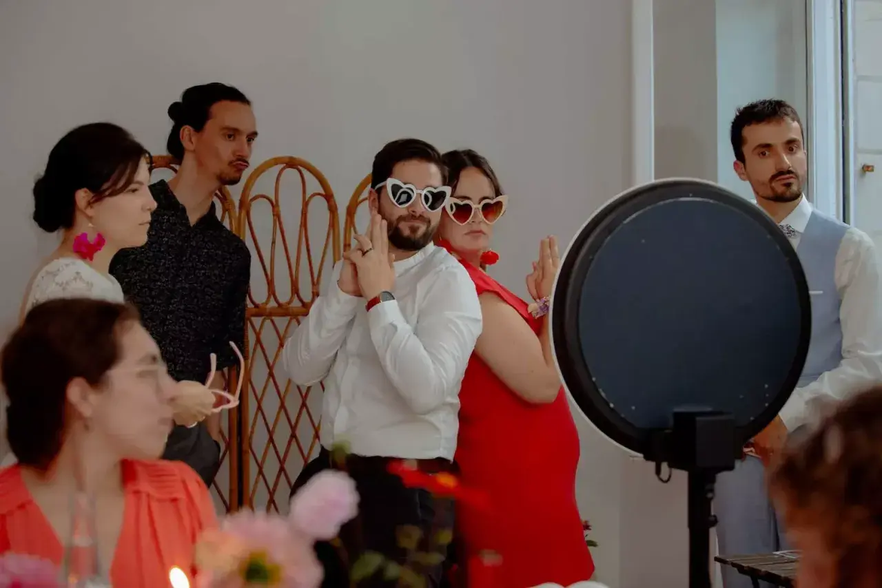 Des invités s'amusent avec des lunettes en forme de cœur lors d'un repas enfant mariage.