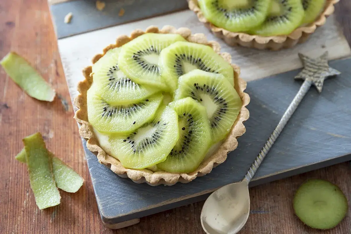 Délicieux dessert kiwi, une tartelette garnie de crème et de fines rondelles de kiwi, prête à être dégustée.