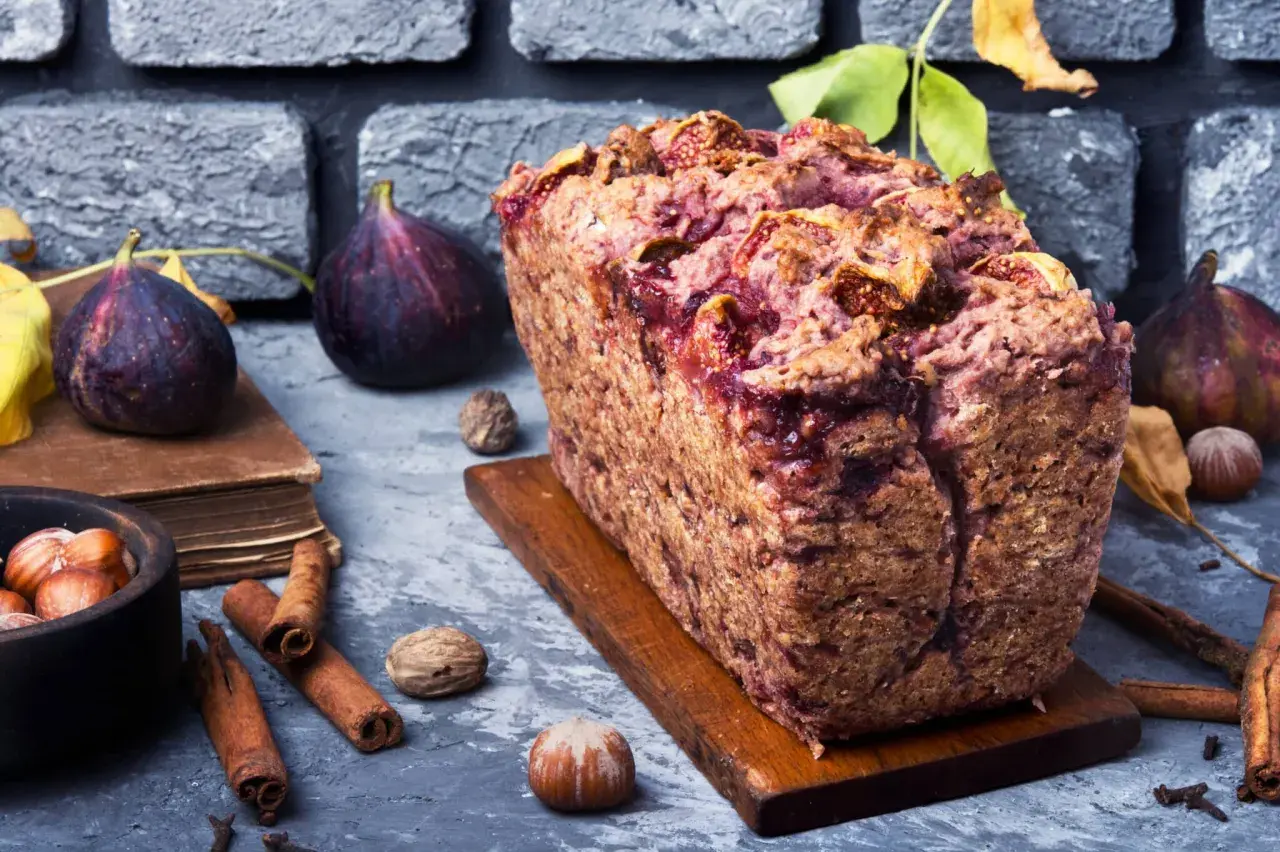 Gâteau rustique aux figues et noix, garni de fruits frais, de cannelle et de noisettes.