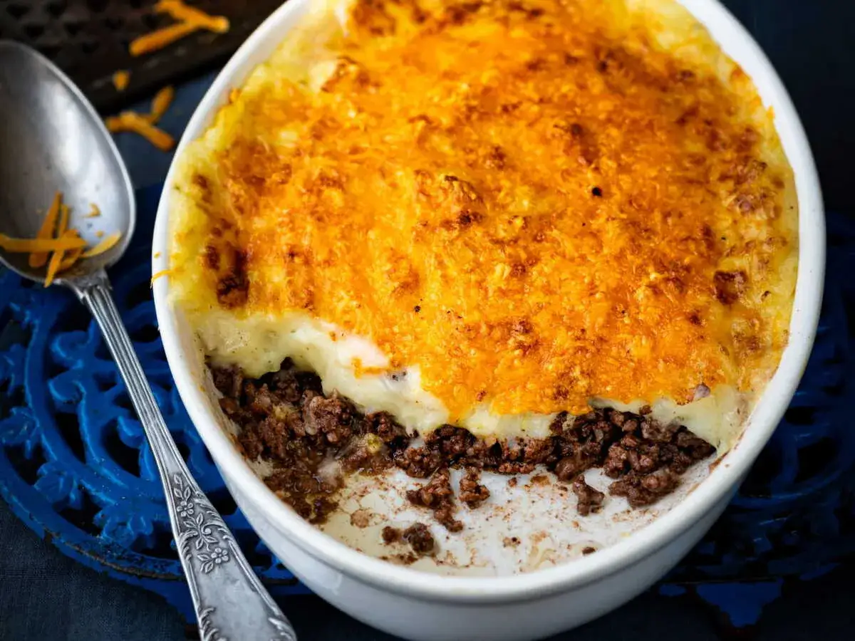 Hachis Parmentier doré et gratiné, prêt à être dégusté après sa cuisson chaleur tournante. Une cuillère en argent est posée à côté.