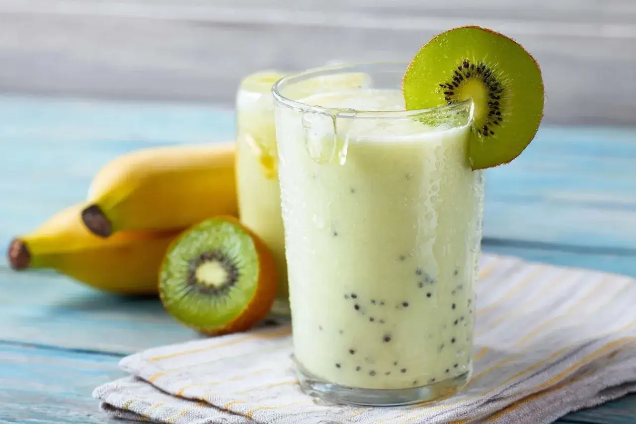 Smoothie vert crémeux à base de kiwi trop mûr et banane, garni d'une tranche de kiwi. Parfait pour une recette rapide et rafraîchissante.