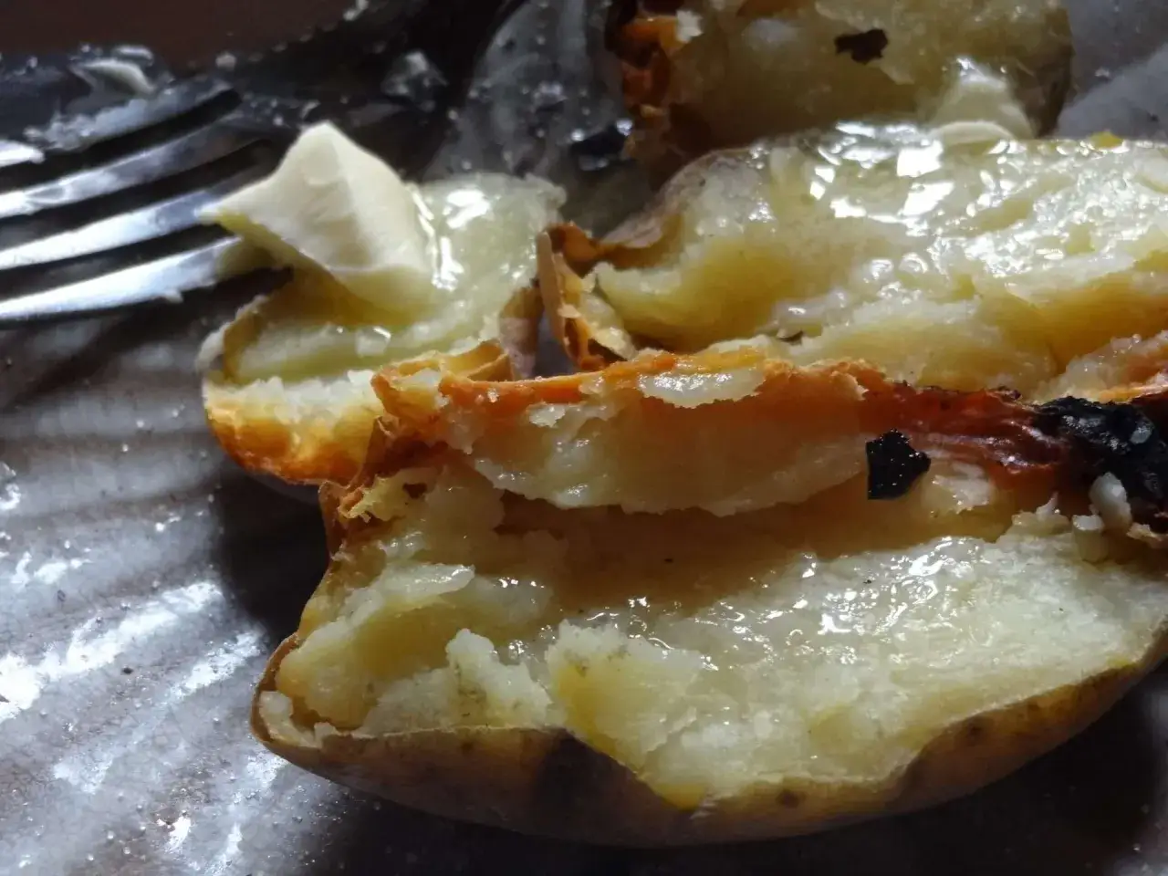 Pommes de terre cuites dans la cendre, fondantes et savoureuses, prêtes à être dégustées avec une touche de beurre.