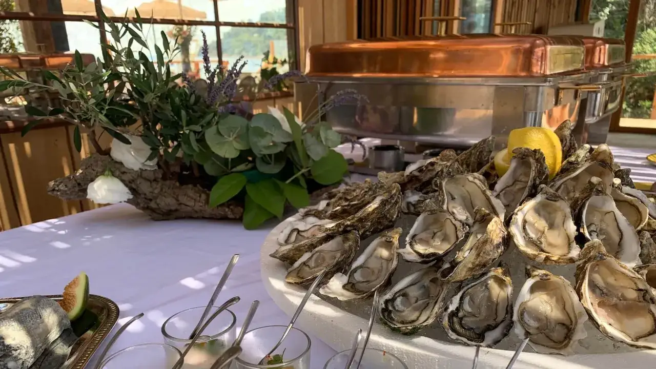 Présentation de fruits de mer pour mariage : huîtres fraîches sur glace, citron, et un buffet de mariage en arrière-plan.