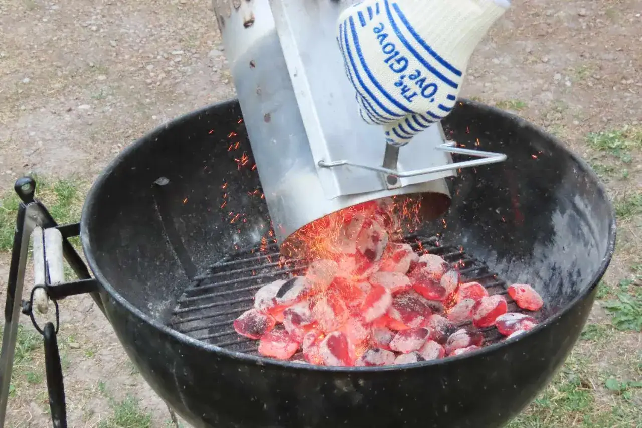 Des braises rouges tombent d'un allume-feu dans un barbecue. C'est la première étape pour savoir comment allumer un barbecue.