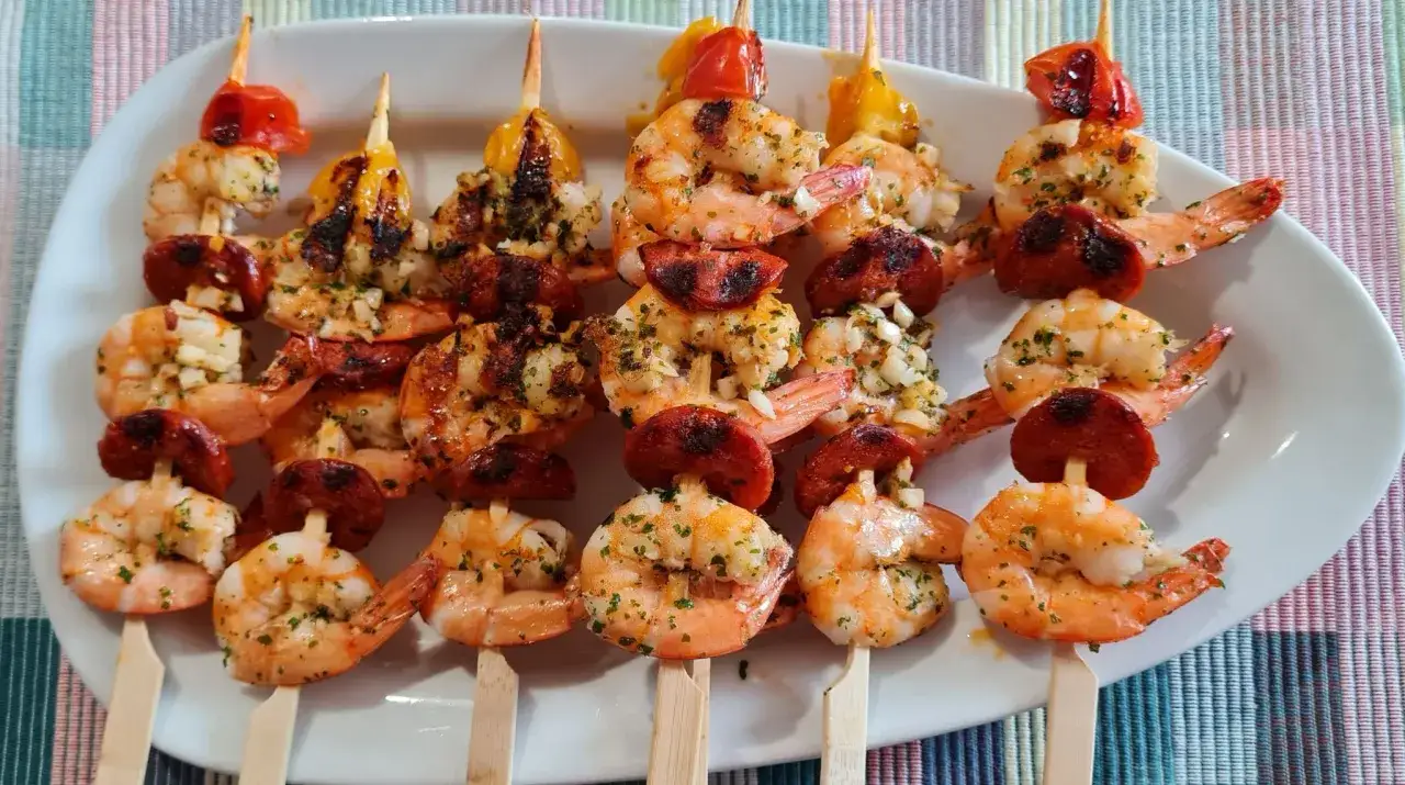 Brochettes crevette chorizo grillées, garnies d'ail et de persil, prêtes à être dégustées.
