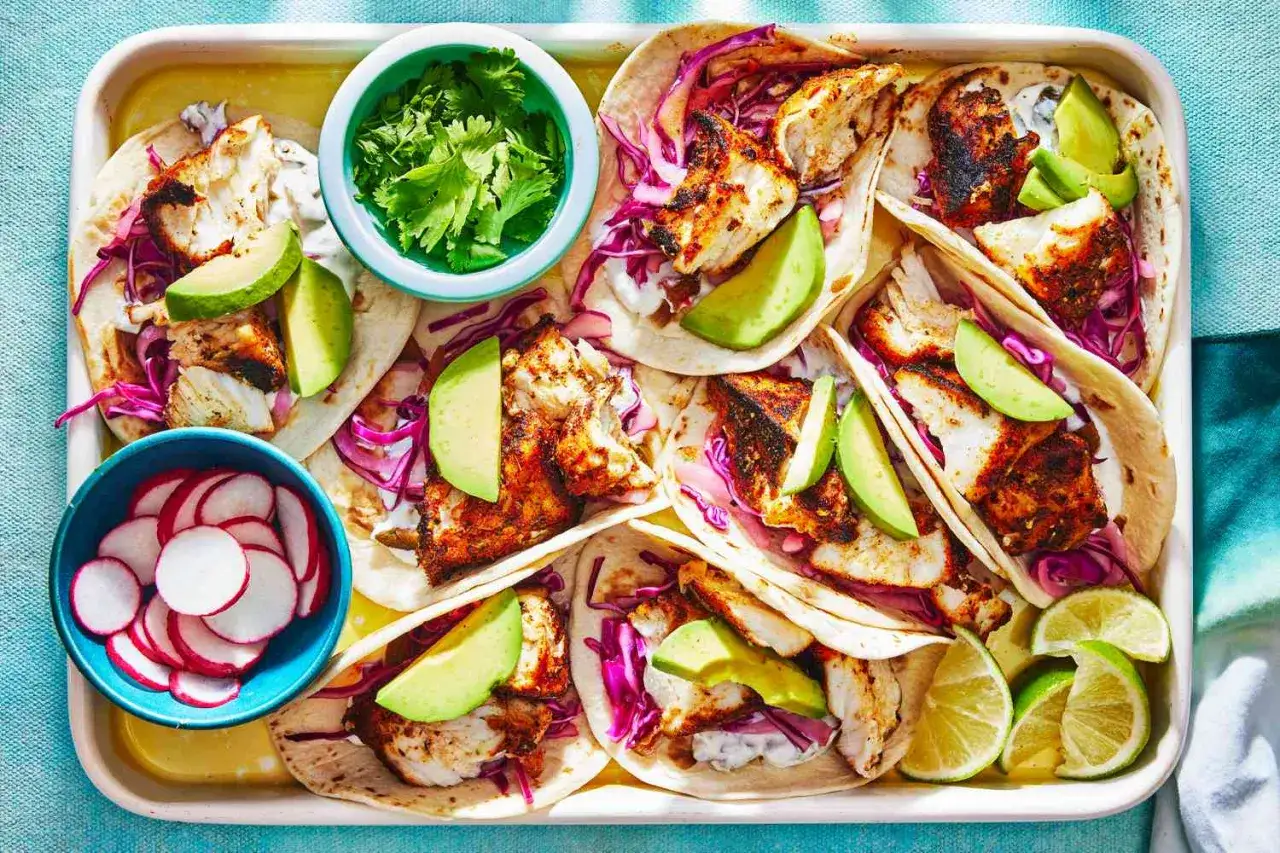 Un plateau de tacos au poisson grillé, avocat, chou rouge et radis. Un repas frais et coloré, parfait pour un déjeuner ensoleillé.